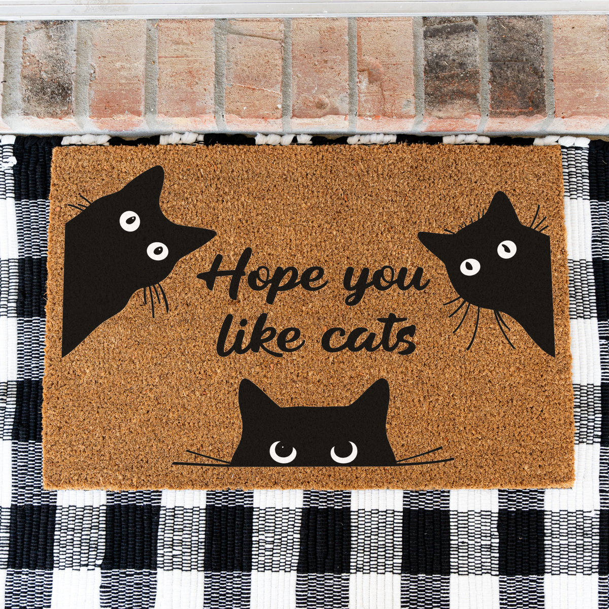 Hope You Like Cats coir doormat with three peeking black cats on a black and white buffalo check rug, close view