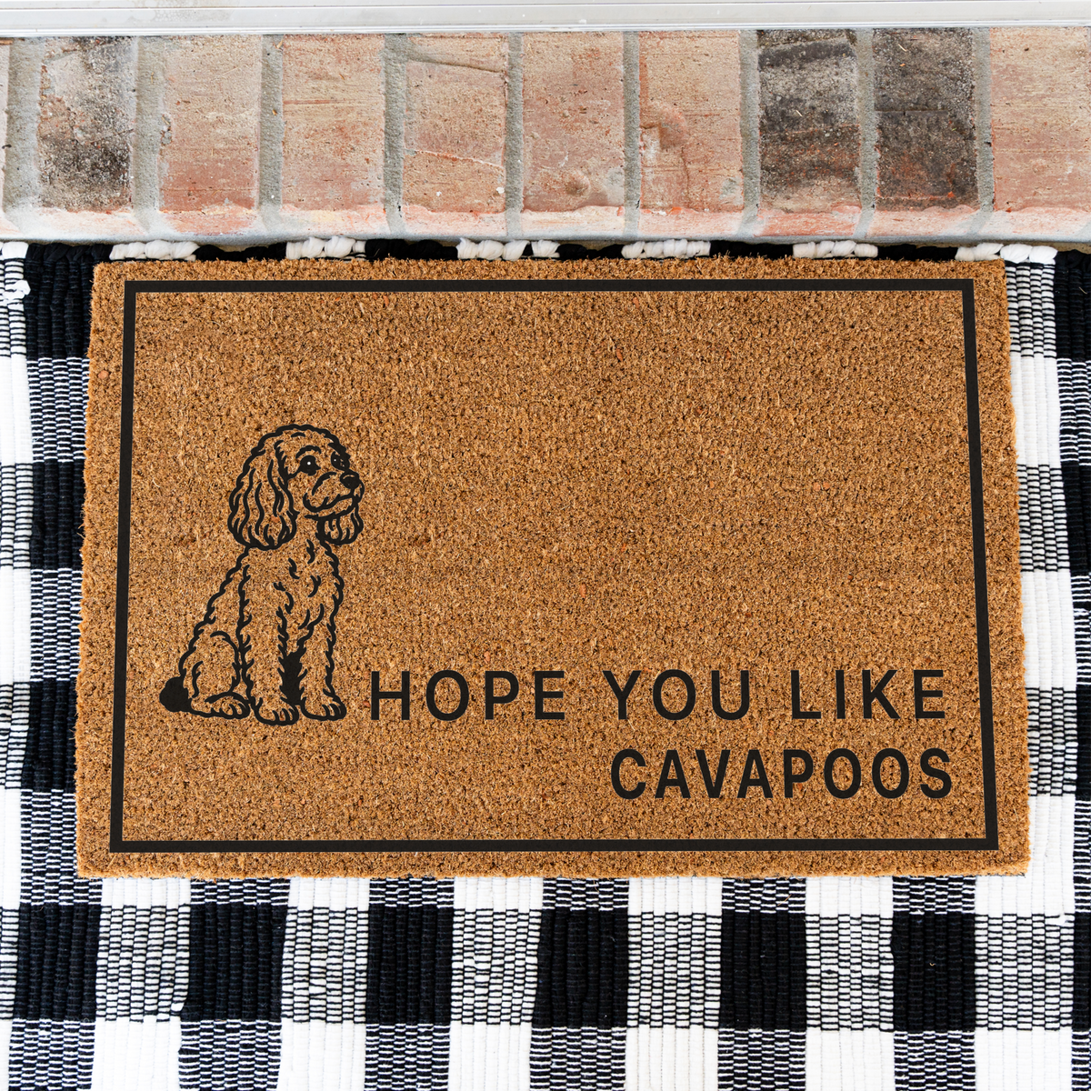 Hope You Like Cavapoos coir doormat with a drawing of a sitting Cavapoo on a black and white buffalo check rug, close view