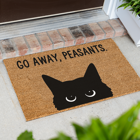 Go Away, Peasants black cat coir doormat at an angle on a front porch by a brick step