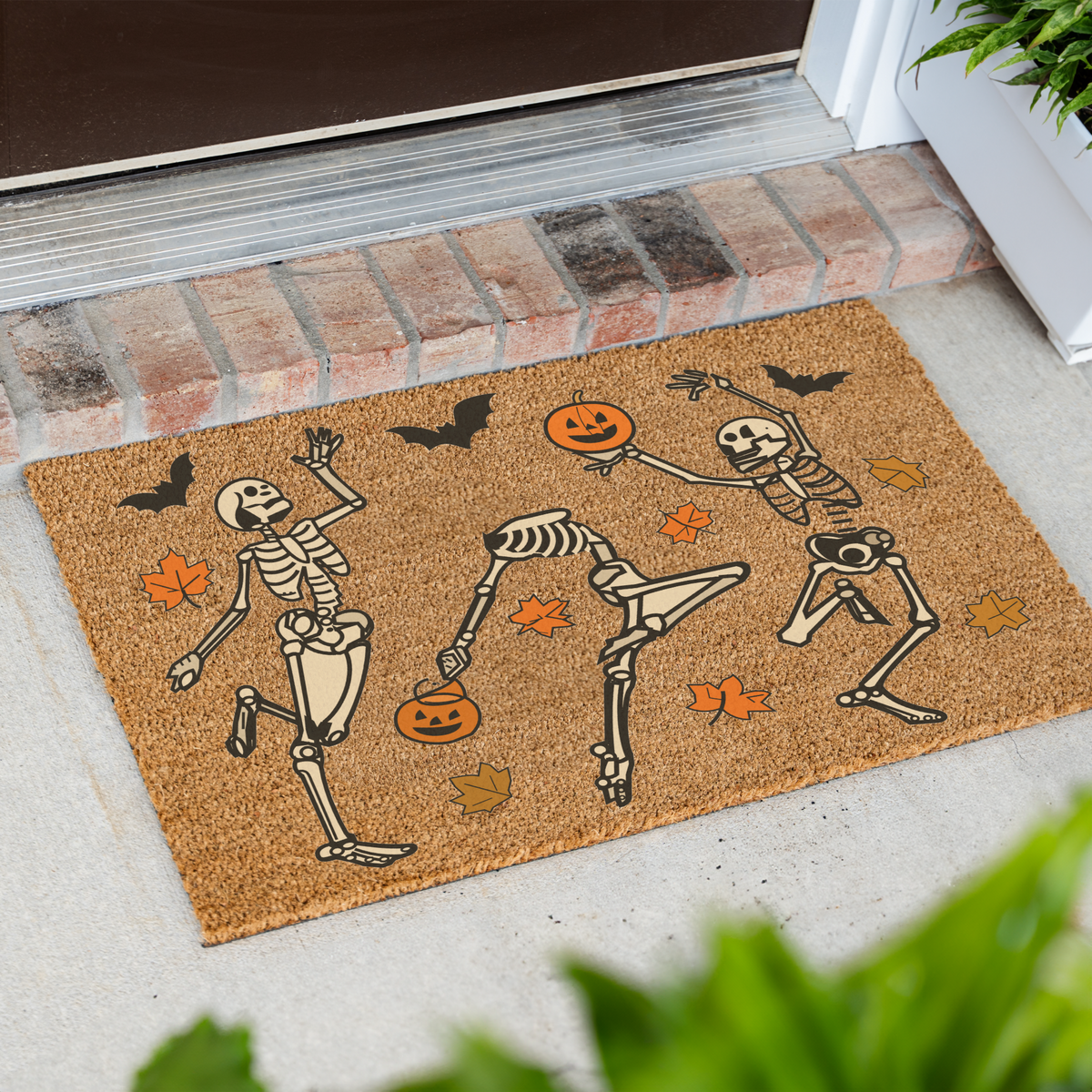 Dancing skeletons Halloween coir doormat at an angle on a front porch by a brick step