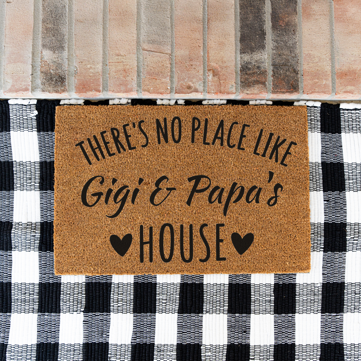 There's No Place Like Gigi & Papa's House coir doormat on a black and white buffalo check rug at a brick step