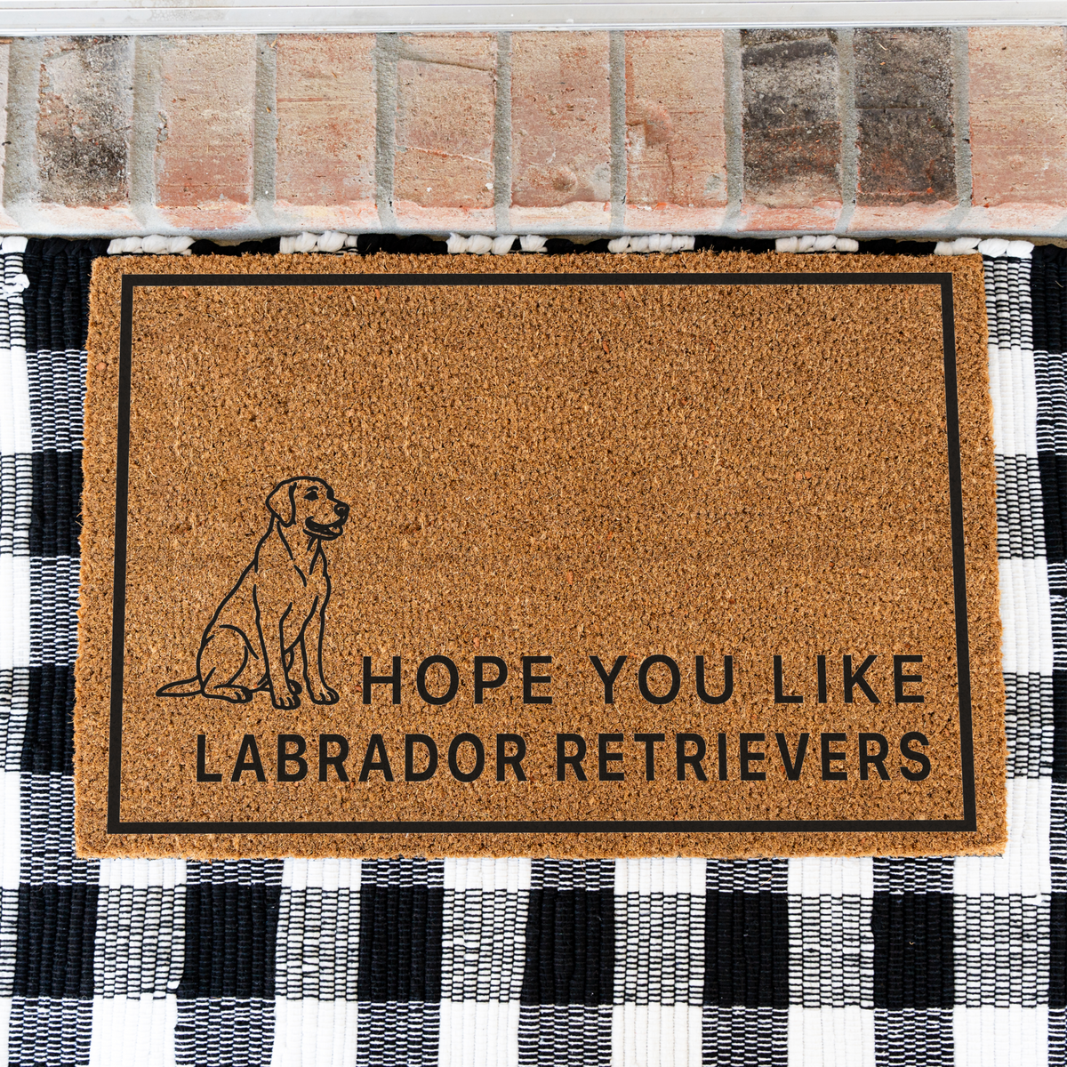 Hope You Like Labrador Retrievers coir doormat with a drawing of a sitting Labrador retriever on a black and white buffalo check rug, close view