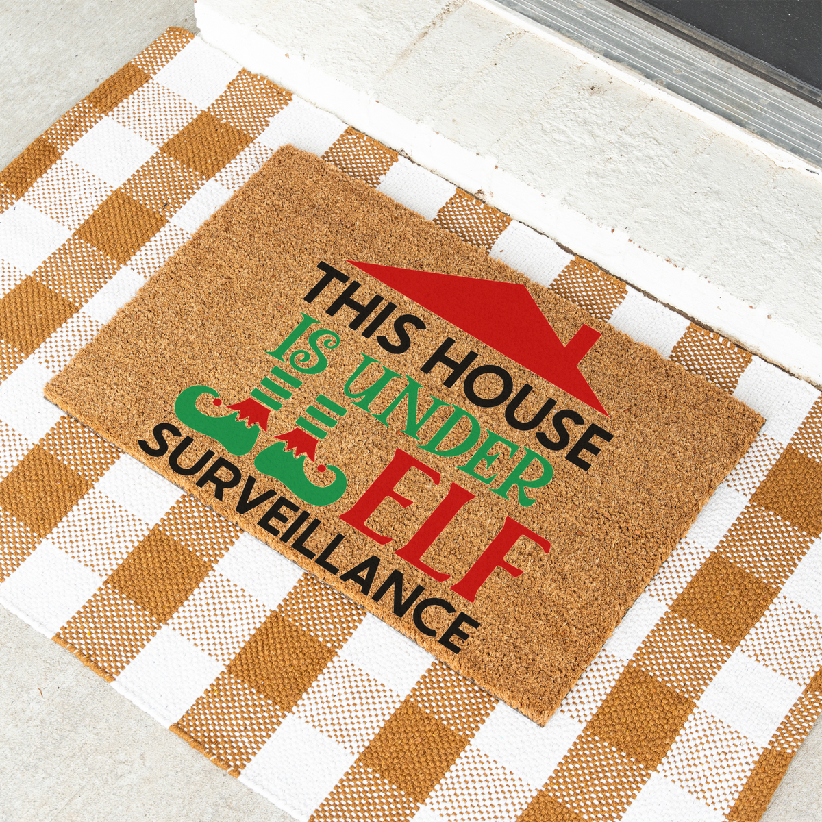 This House Is Under Elf Surveillance coir doormat on a tan and white check rug