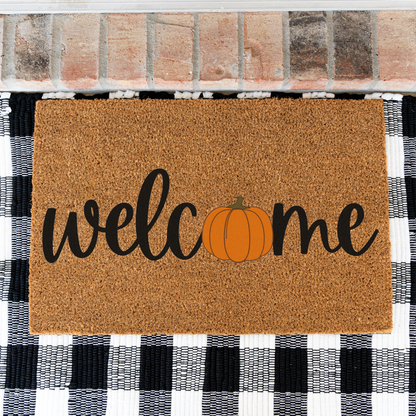 Welcome pumpkin coir doormat on a black and white buffalo check rug, close view