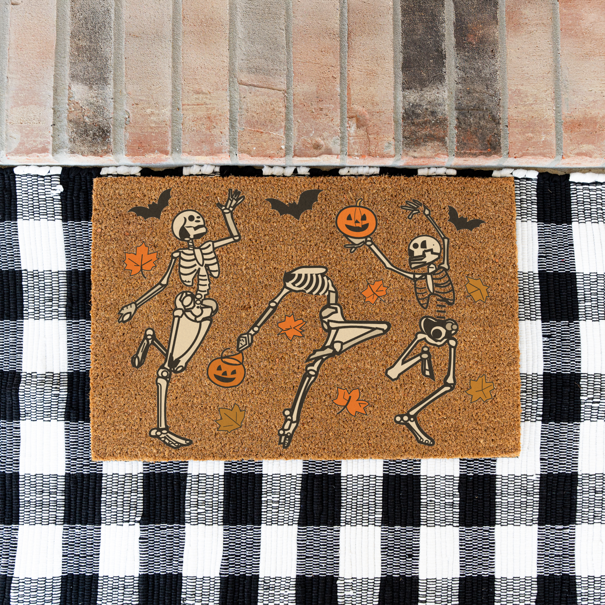 Dancing skeletons Halloween coir doormat on a black and white buffalo check rug at a brick step
