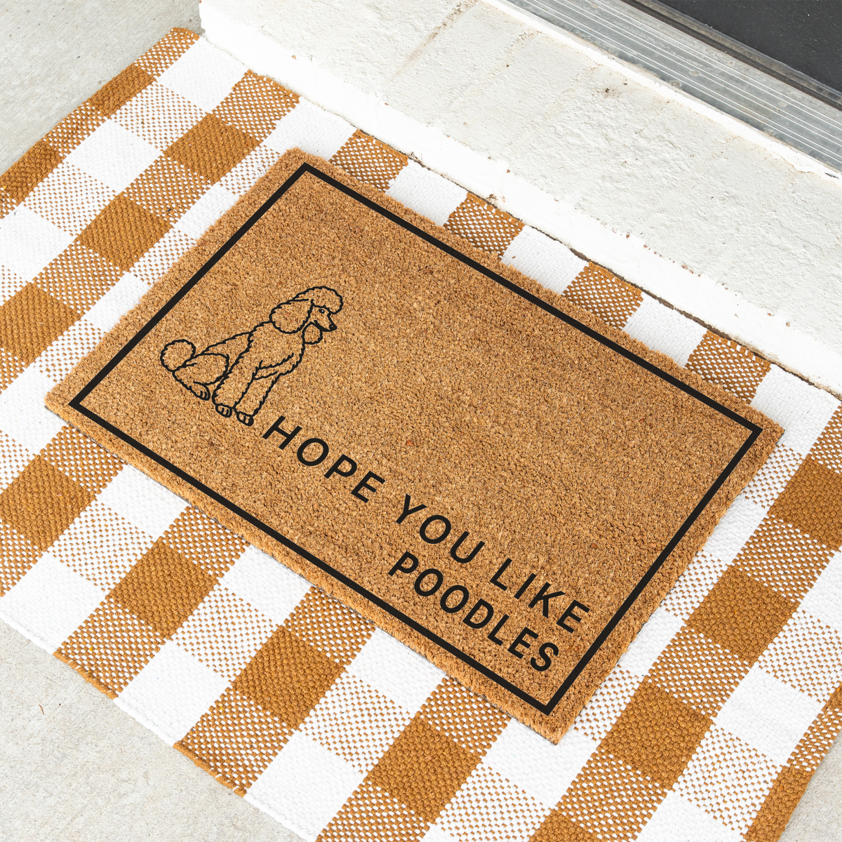 Hope You Like Poodles coir doormat with a drawing of a sitting poodle at an angle on a tan and white check rug