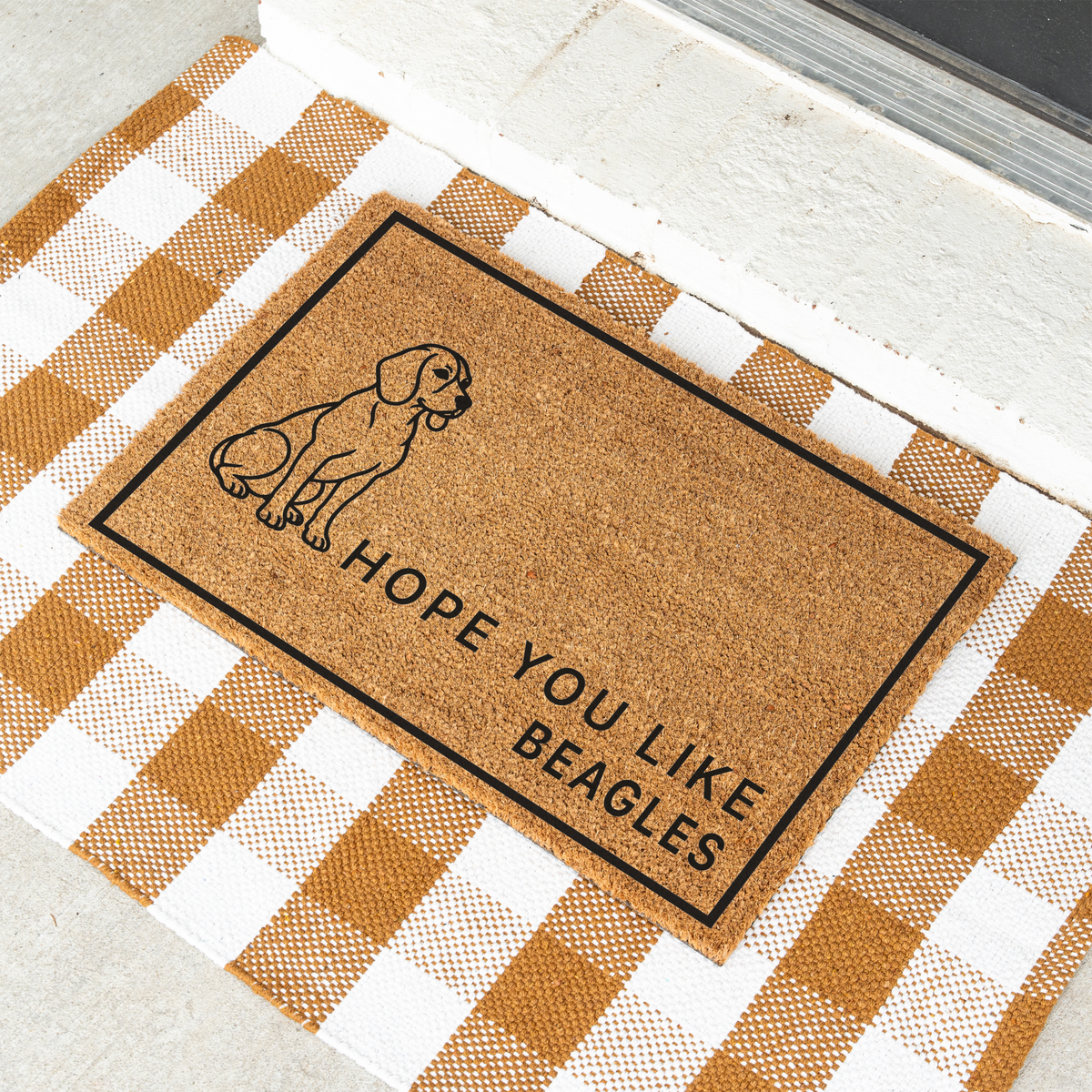Hope You Like Beagles coir doormat with a drawing of a sitting beagle at an angle on a tan and white check rug