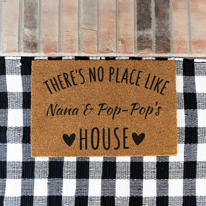 There's No Place Like Nana & Pop-Pop's House coir doormat on a black and white buffalo check rug at a brick step