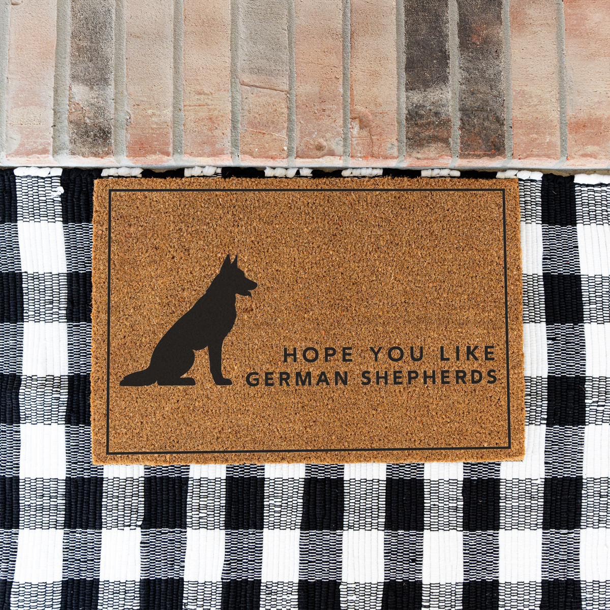 Hope You Like German Shepherds silhouette coir doormat with a thin black border on a black and white buffalo check rug at a brick step