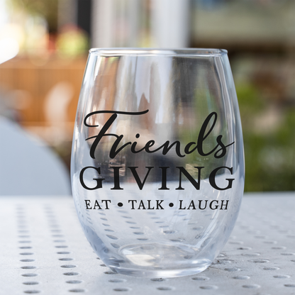 Friendsgiving stemless wine glass, empty, on a perforated metal patio table