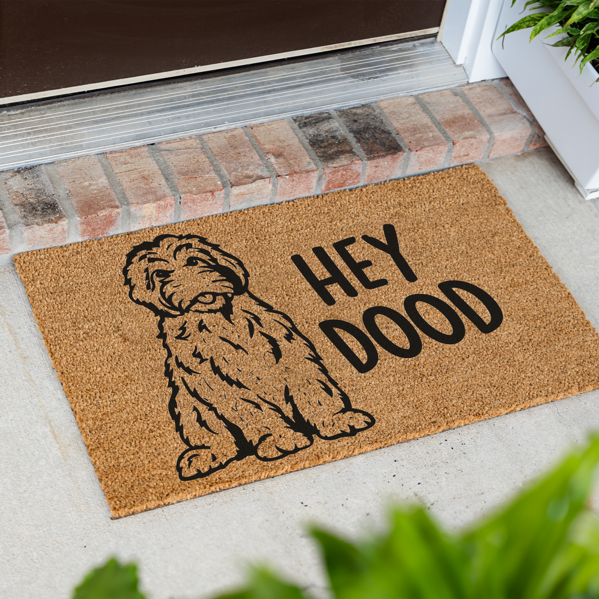 Hey Dood doodle dog coir doormat at an angle on a front porch by a brick step