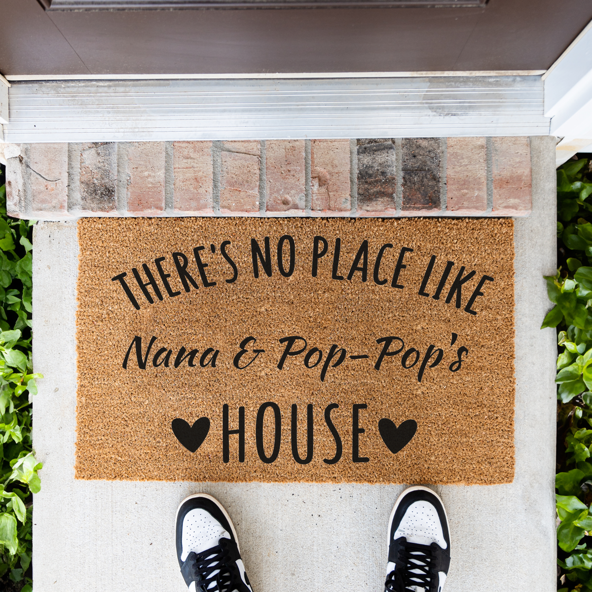 There's No Place Like Nana & Pop-Pop's House coir doormat in front of a brick step, top-down view