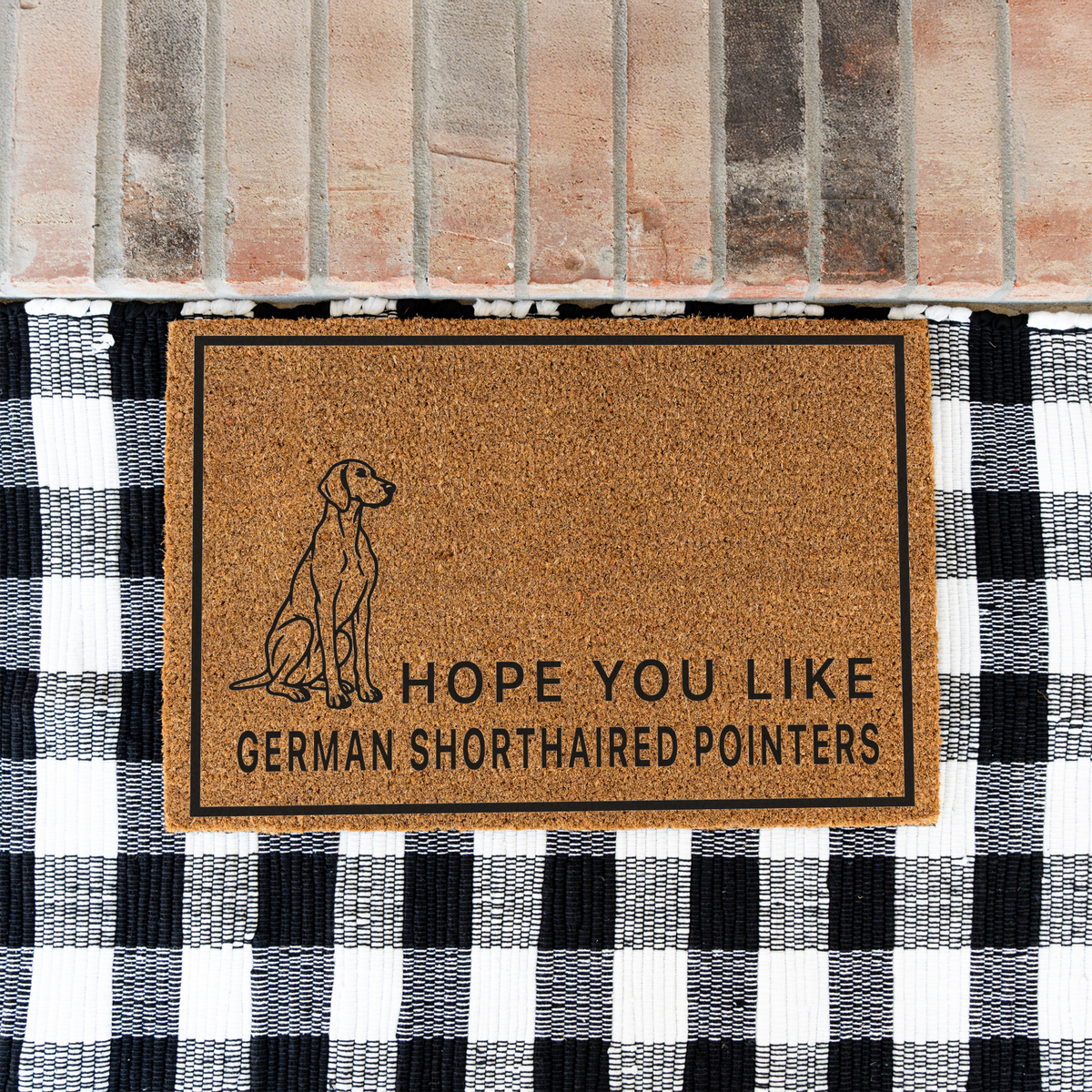 Hope You Like German Shorthaired Pointers coir doormat with a drawing of a sitting German shorthaired pointer on a black and white buffalo check rug at a brick step