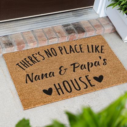 There's No Place Like Nana & Papa's House coir doormat at an angle on a front porch by a brick step
