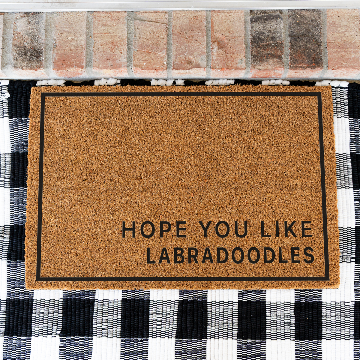 Hope You Like Labradoodles minimalist coir doormat with a thin black border on a black and white buffalo check rug, close view