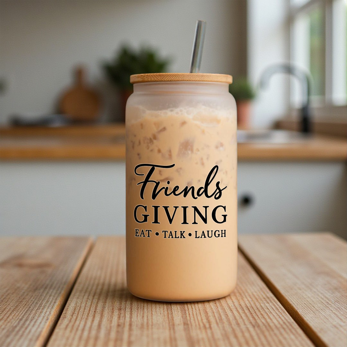 Friendsgiving 16 oz frosted glass can with a bamboo lid and straw, filled with iced coffee, on a kitchen counter