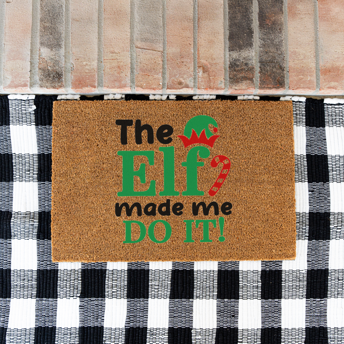 The Elf Made Me Do It coir doormat on a black and white buffalo check rug at a brick step