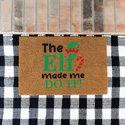 The Elf Made Me Do It coir doormat on a black and white buffalo check rug at a brick step