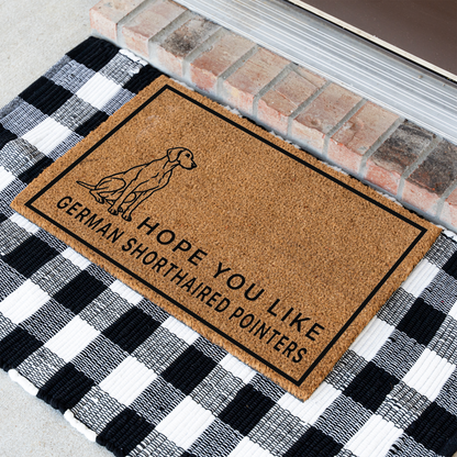 Hope You Like German Shorthaired Pointers coir doormat with a drawing of a sitting German shorthaired pointer at an angle on a black and white buffalo check rug
