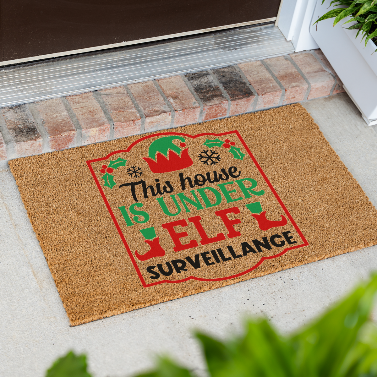 This House Is Under Elf Surveillance framed coir doormat at an angle in front of a brick step