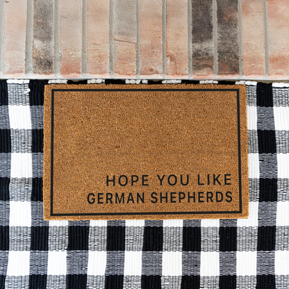 Hope You Like German Shepherds minimalist coir doormat with a thin black border on a black and white buffalo check rug at a brick step