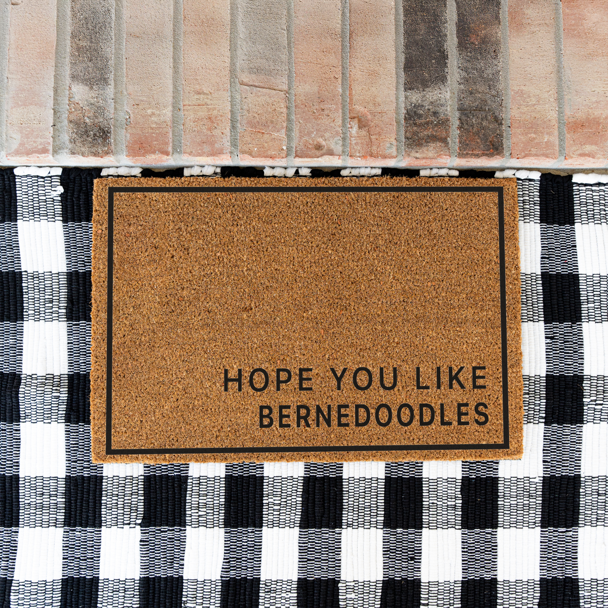 Hope You Like Bernedoodles minimalist coir doormat with a thin black border on a black and white buffalo check rug at a brick step