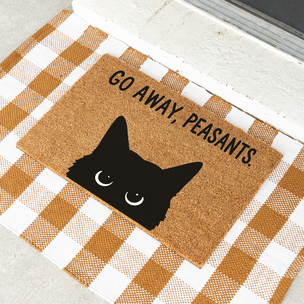 Go Away, Peasants black cat coir doormat on a tan and white check rug