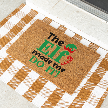 The Elf Made Me Do It coir doormat on a tan and white check rug