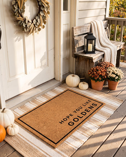 Hope You Like Goldens minimalist coir doormat on a striped jute rug on a styled fall porch