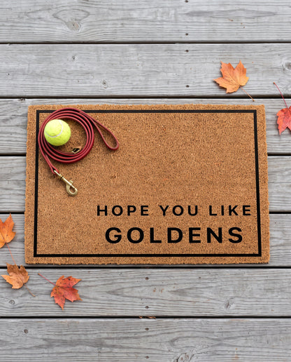 Hope You Like Goldens minimalist coir doormat with a tennis ball and dog leash on it