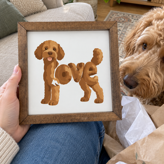 Standing Doodle Love square sign in a walnut frame held above a lap with gift wrap and an apricot doodle dog